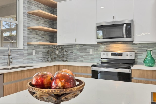 kitchen featuring a sink, open shelves, stainless steel appliances, light countertops, and decorative backsplash