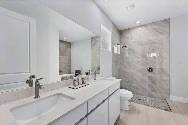 full bathroom with toilet, tiled shower, visible vents, and a sink