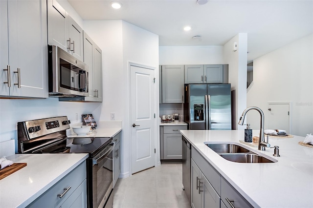 kitchen with appliances with stainless steel finishes, gray cabinets, and a sink