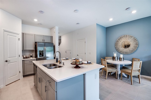 kitchen with stainless steel appliances, gray cabinets, light countertops, and a sink