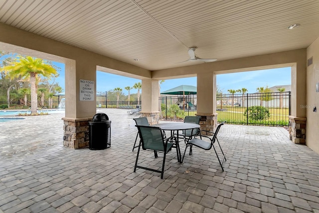 view of patio / terrace featuring a ceiling fan, outdoor dining area, fence, and a community pool