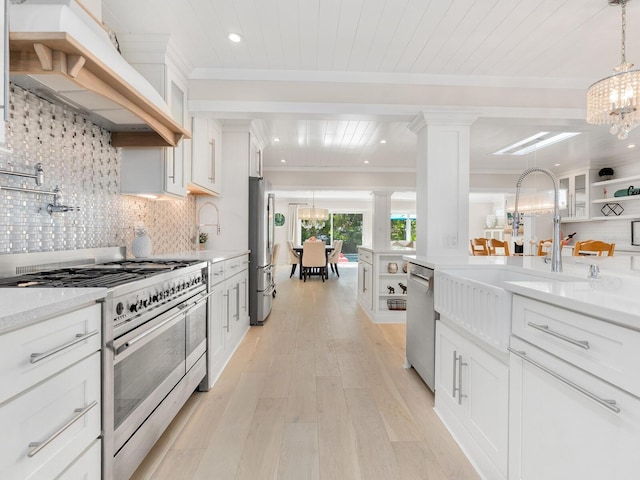 kitchen featuring crown molding, stainless steel appliances, custom exhaust hood, and an inviting chandelier