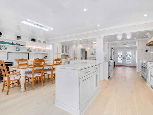 kitchen with light countertops, light wood-style flooring, stainless steel stove, and white cabinetry