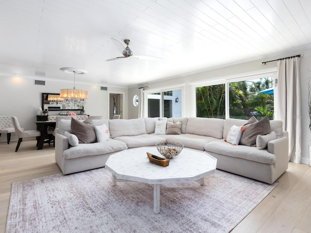 living room with visible vents, crown molding, light wood-style flooring, and ceiling fan with notable chandelier