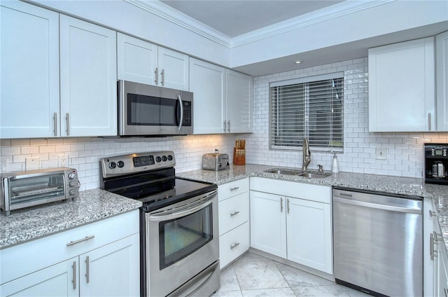 kitchen featuring backsplash, appliances with stainless steel finishes, ornamental molding, white cabinetry, and a sink