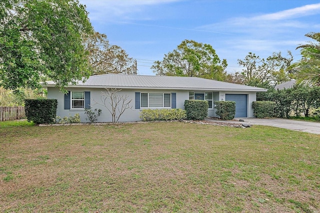 ranch-style house featuring metal roof, an attached garage, driveway, stucco siding, and a front lawn