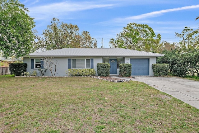 ranch-style house with metal roof, a garage, driveway, stucco siding, and a front yard