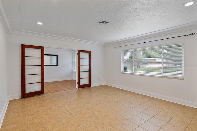 empty room with visible vents, crown molding, a textured ceiling, and baseboards