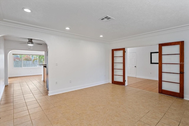 spare room featuring arched walkways, crown molding, visible vents, ceiling fan, and a textured ceiling