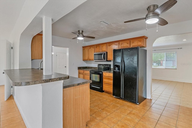 kitchen featuring light tile patterned floors, dark countertops, visible vents, a peninsula, and black appliances