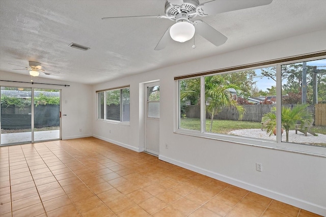 unfurnished room featuring a textured ceiling, light tile patterned floors, visible vents, and baseboards