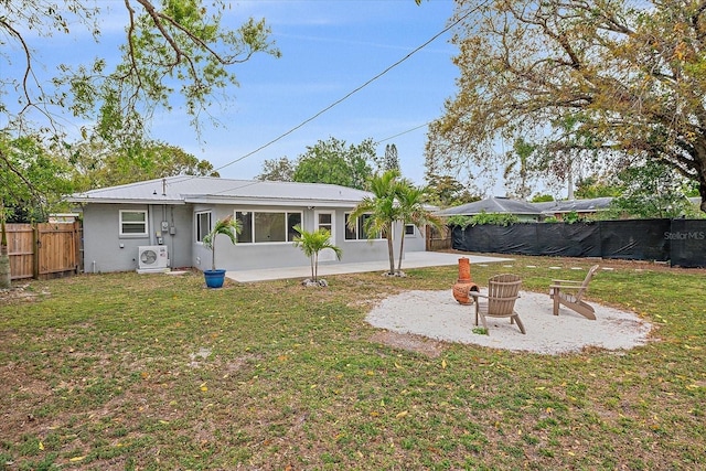 back of house featuring an outdoor fire pit, a lawn, a fenced backyard, and a patio