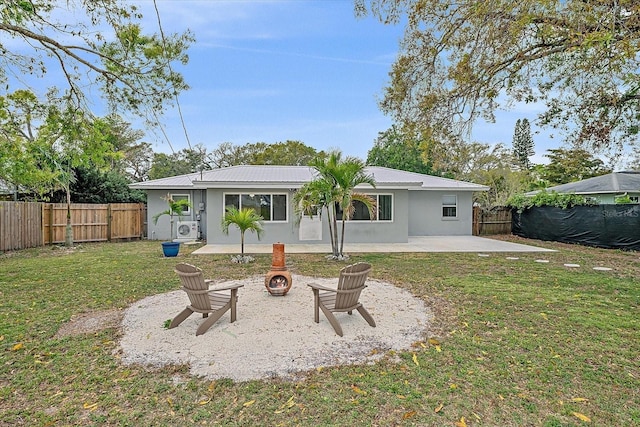 rear view of house with an outdoor fire pit, a lawn, a fenced backyard, a patio area, and stucco siding