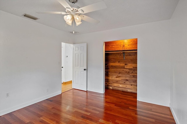 unfurnished bedroom featuring a closet, visible vents, baseboards, and wood finished floors