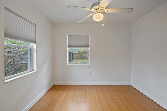 spare room featuring a wealth of natural light, baseboards, ceiling fan, and light wood finished floors