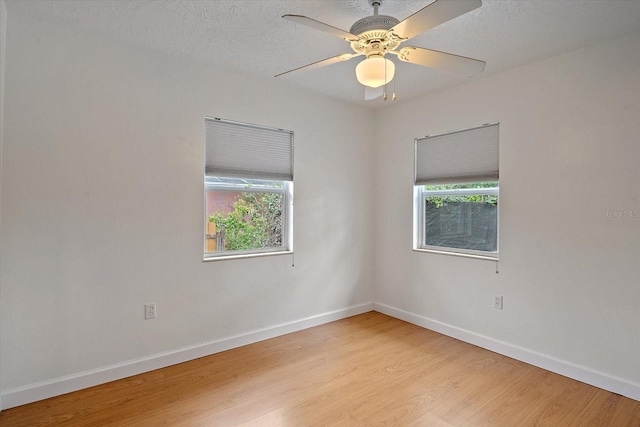 spare room with light wood finished floors, a ceiling fan, baseboards, and a textured ceiling