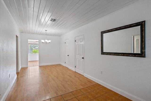 empty room with baseboards, visible vents, wooden ceiling, wood finished floors, and a chandelier