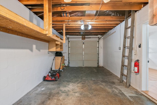 garage featuring concrete block wall and a garage door opener