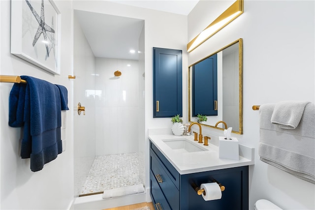 bathroom with toilet, vanity, and a tile shower