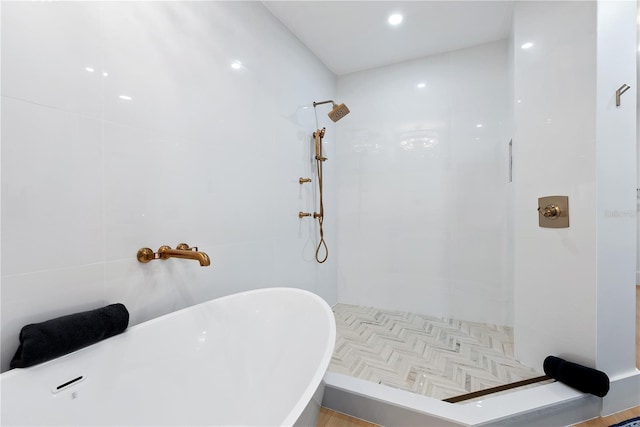 full bath with a soaking tub and tiled shower