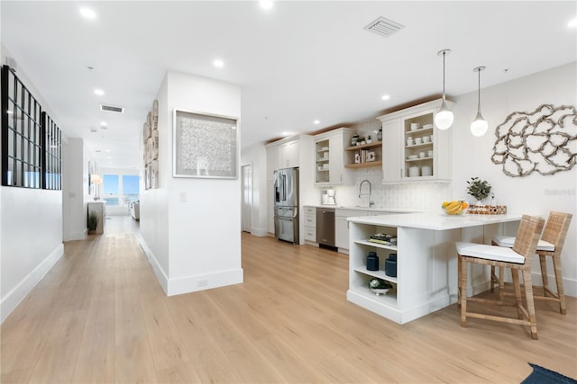 kitchen featuring open shelves, a peninsula, visible vents, and stainless steel appliances