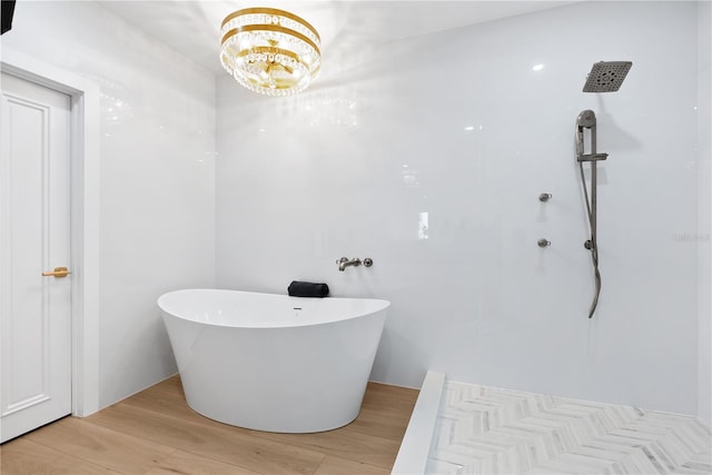 full bath with a shower, a soaking tub, an inviting chandelier, and wood finished floors