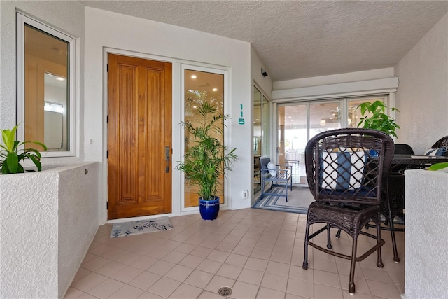 foyer with light tile patterned floors, a textured ceiling, and a textured wall