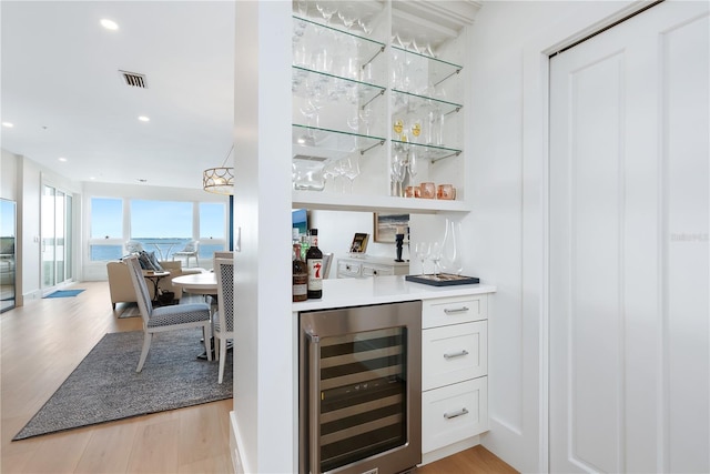 bar with visible vents, recessed lighting, wine cooler, light wood-style floors, and a bar