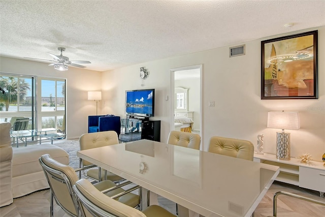 dining space with visible vents, ceiling fan, and a textured ceiling