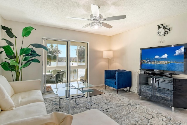 living area with a ceiling fan and a textured ceiling