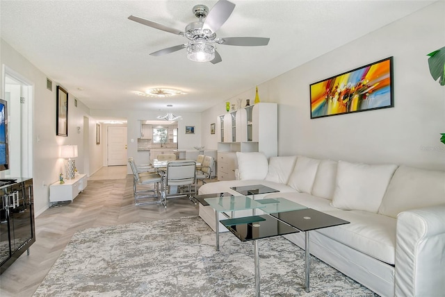 living area featuring ceiling fan, visible vents, and a textured ceiling