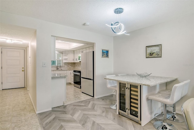 kitchen with a peninsula, wine cooler, a sink, and freestanding refrigerator