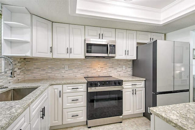 kitchen featuring appliances with stainless steel finishes, ornamental molding, white cabinetry, a sink, and a textured ceiling