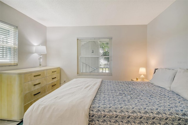 bedroom with a textured ceiling and multiple windows