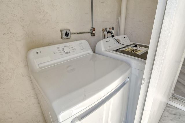 clothes washing area with marble finish floor, laundry area, and separate washer and dryer