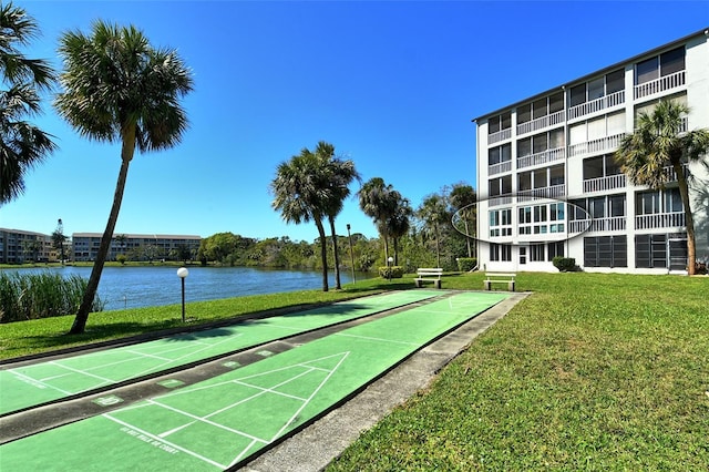 surrounding community with a water view, shuffleboard, and a lawn