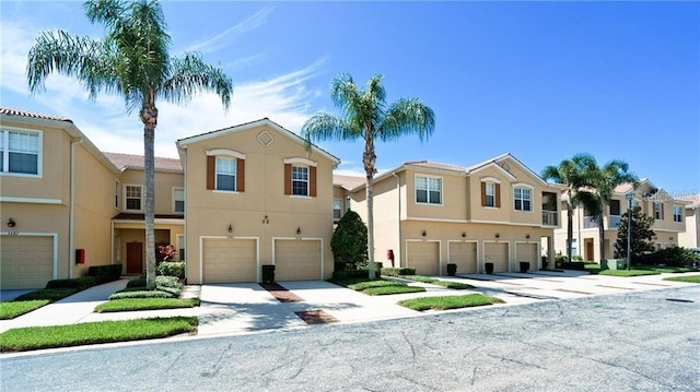 view of property with a garage, driveway, a residential view, and stucco siding