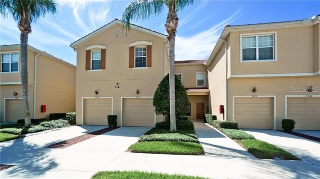 multi unit property with driveway, an attached garage, and stucco siding