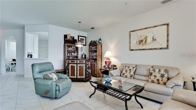 living area with arched walkways, marble finish floor, and visible vents