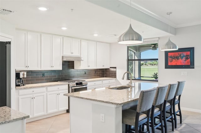 kitchen with tasteful backsplash, visible vents, light stone counters, under cabinet range hood, and a sink