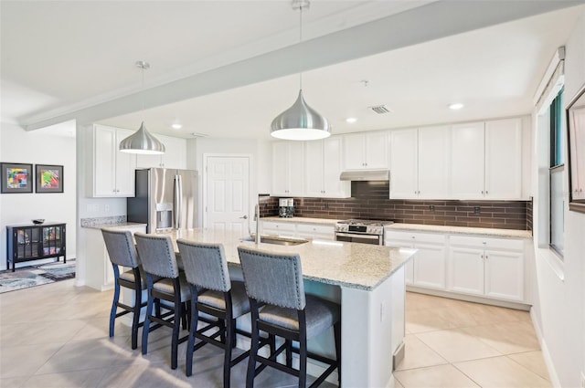 kitchen featuring under cabinet range hood, decorative backsplash, stainless steel appliances, and a sink