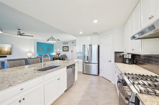 kitchen with backsplash, appliances with stainless steel finishes, white cabinets, a sink, and under cabinet range hood