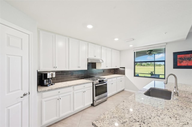 kitchen with decorative backsplash, white cabinets, a sink, gas range, and under cabinet range hood