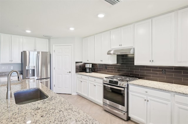 kitchen featuring appliances with stainless steel finishes, a sink, under cabinet range hood, and decorative backsplash