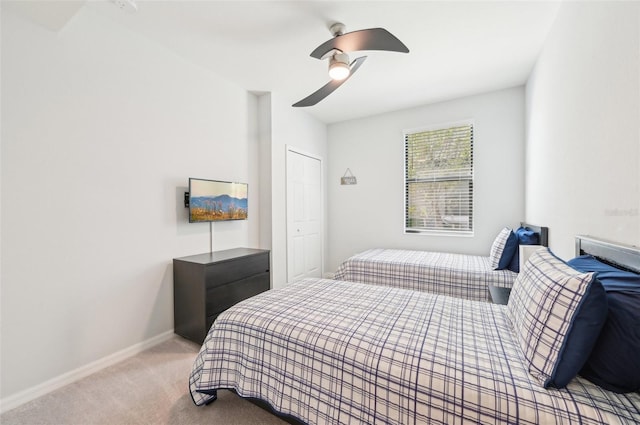 bedroom with baseboards, ceiling fan, a closet, and light colored carpet