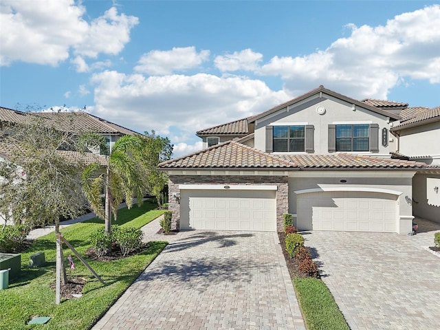 mediterranean / spanish house with a tiled roof, decorative driveway, and stucco siding