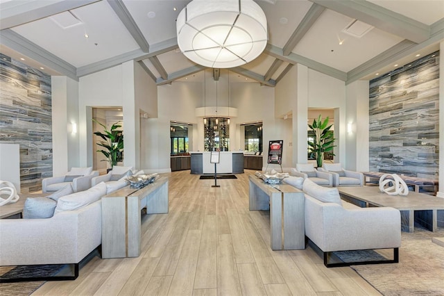 living room featuring an accent wall, high vaulted ceiling, and wallpapered walls