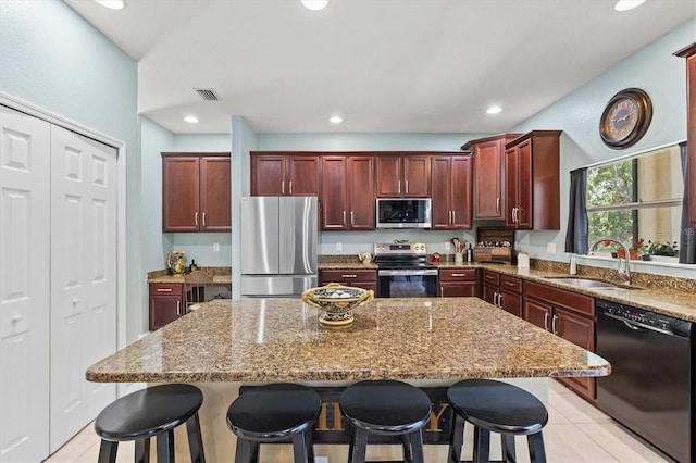 6156 41st St E, Bradenton, FL 34203 - kitchen with appliances with stainless steel finishes, reddish brown cabinets, light stone countertops, a center island, and recessed lighting