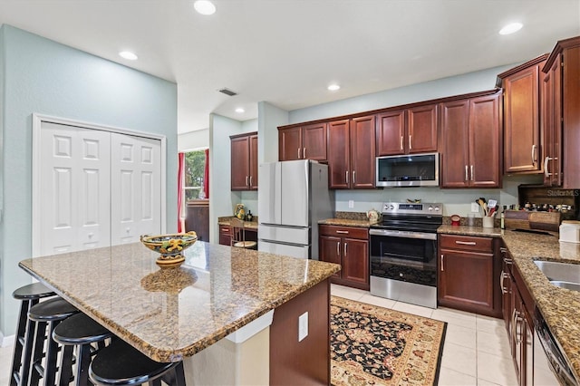 6156 41st St E, Bradenton, FL 34203 - kitchen with stainless steel appliances, stone countertops, light tile patterned floors, a breakfast bar area, and recessed lighting