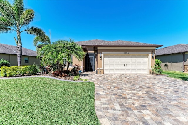 view of front of house featuring a garage, a shingled roof, stucco siding, decorative driveway, and a front yard